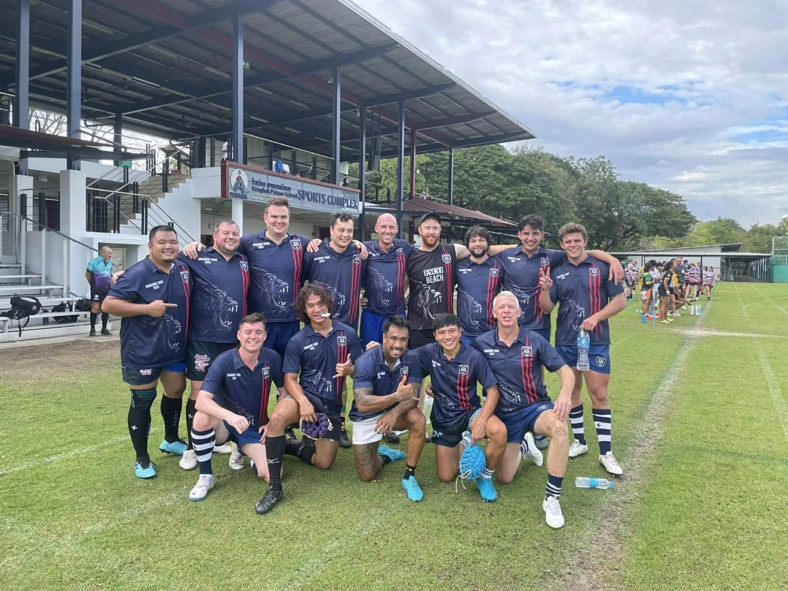 The Da Nang Guerilla squad together on the grass in navy club shirts, smiling